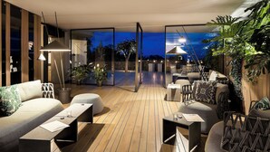 Un espace de vie extérieur moderne, doté d’un plancher en bois, d’un coin salon et de plantes en pot.