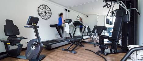 A gym with cardio machines, a treadmill, and weight equipment.