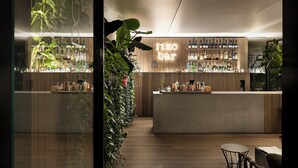 Un espace bar moderne avec des panneaux de bois, un néon et une variété de bouteilles.