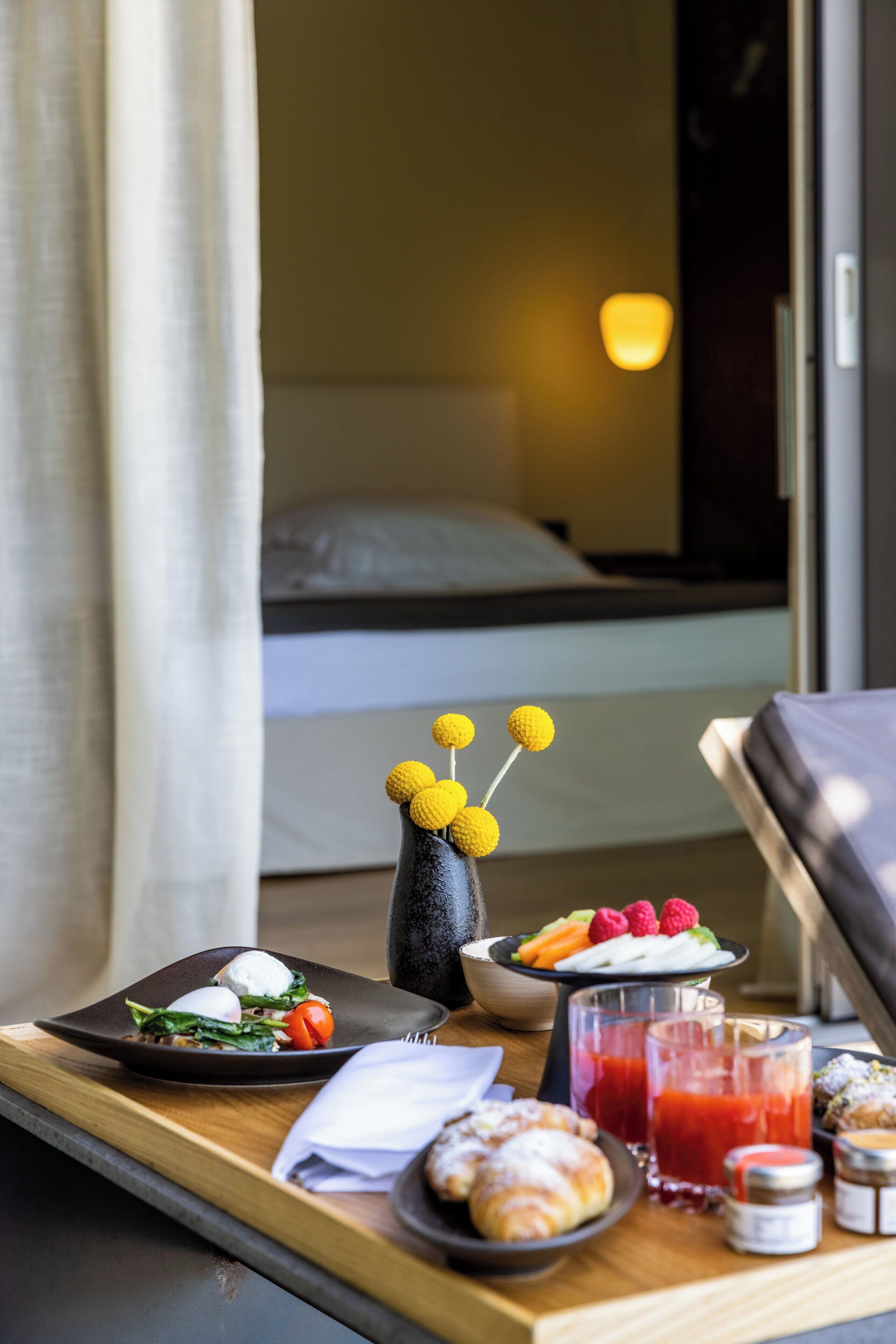 A breakfast tray with food items and a vase with yellow spherical objects.