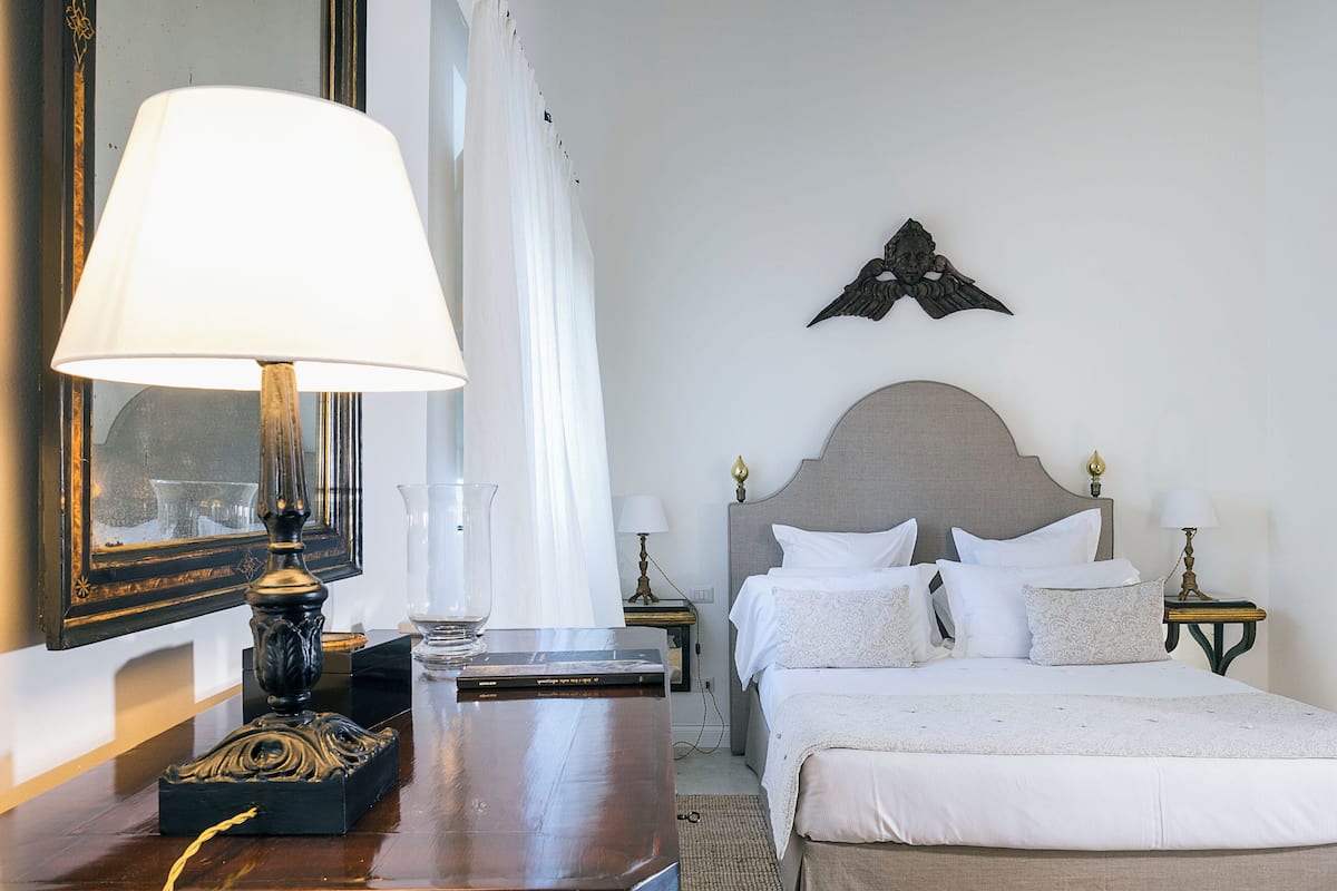 Experience a stylish retreat with a neatly made bed, wooden nightstand, and large mirror.