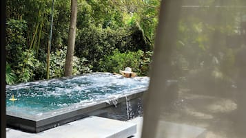 Relax in a serene hot tub surrounded by lush greenery and a soothing waterfall.
