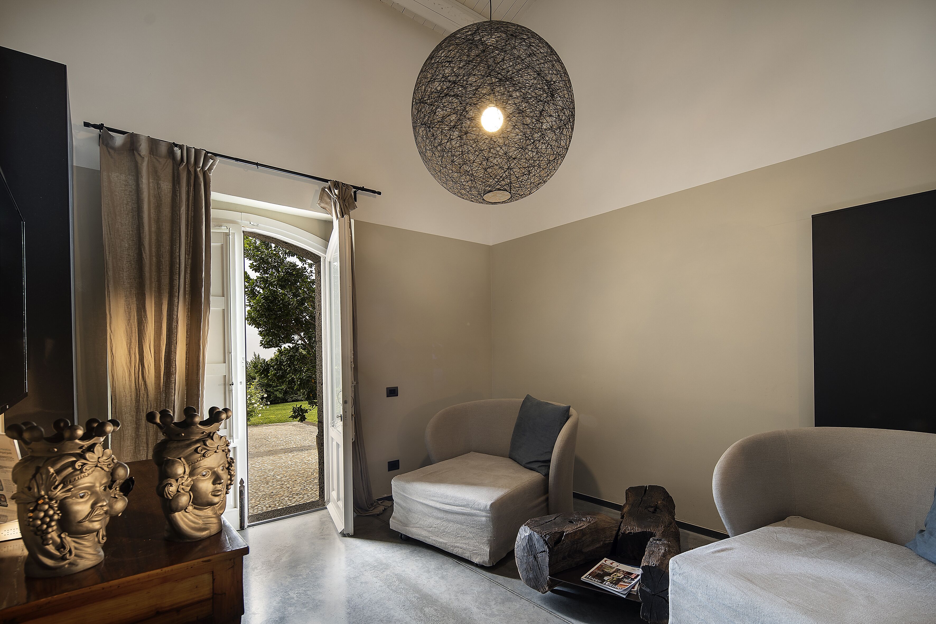Una sala de estar moderna con un sofá, una butaca, una mesa de centro y jarrones decorativos.