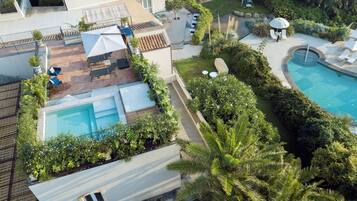 A rooftop pool area with lounge chairs, a small pool, and surrounding greenery.