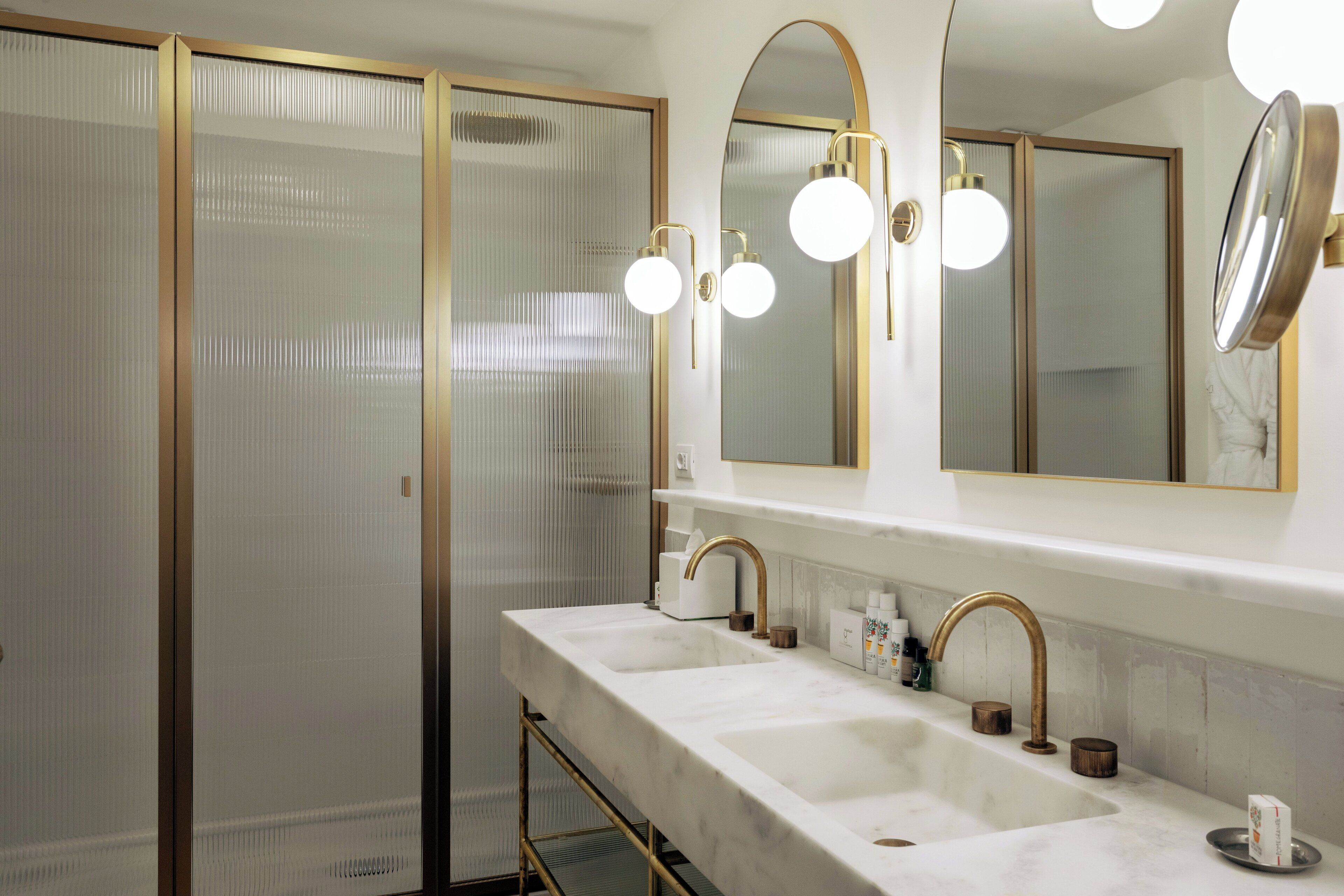 A bathroom with two sinks, a large mirror, and a shower with frosted glass doors.