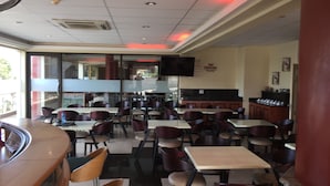 Un restaurante con varias mesas y sillas, una barra y un televisor colgado en la pared.