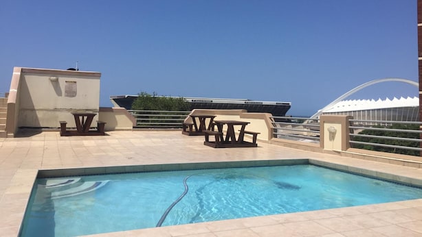 Zona de piscina en la azotea con vistas despejadas al océano, una mesa de billar y un área de descanso.