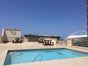 Zona de piscina en la azotea con vistas despejadas al océano, una mesa de billar y un área de descanso.