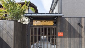 Una valla de madera con un cartel que anuncia Fujitaya B&B en Kioto, indicando que ofrece servicios de bicicletas y yoga.
