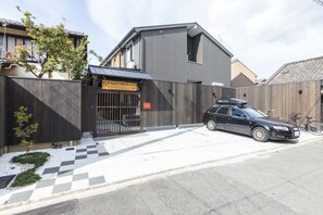 Contemporary building with a sleek entrance, featuring a car and a tree.