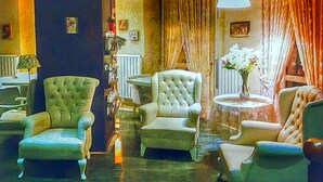 A lobby with a grand staircase, plush armchairs, a round table with a vase of flowers, and a large window with curtains. - Buyukada Princess Hotel (Adalar)