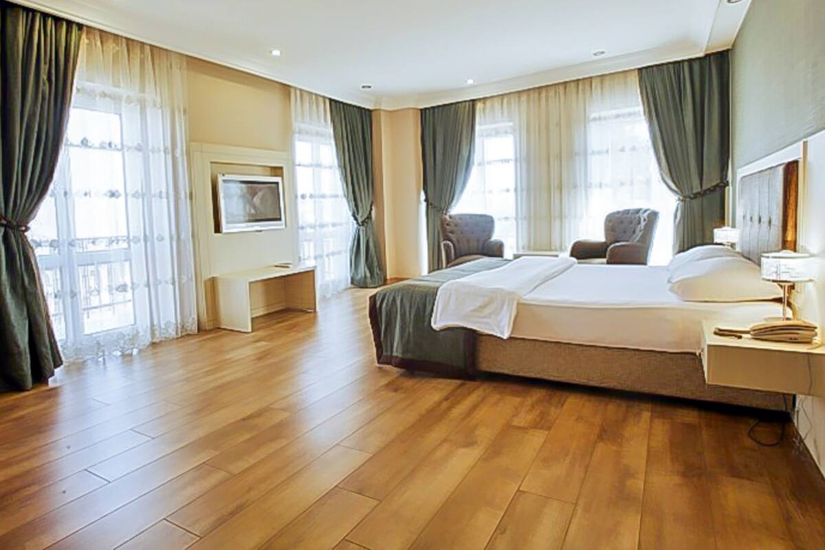 Une chambre d’hôtel avec un grand lit, un bureau, une chaise et un téléviseur.