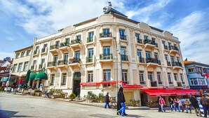 A multi-story building with balconies, a cafe with a red awning, and outdoor seating. - Buyukada Princess Hotel (Adalar)