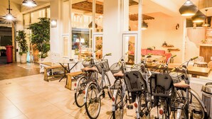 A spacious indoor area with bicycles parked near a large window, a wooden table, and hanging pendant lights. - Tang Villa (Taitung)