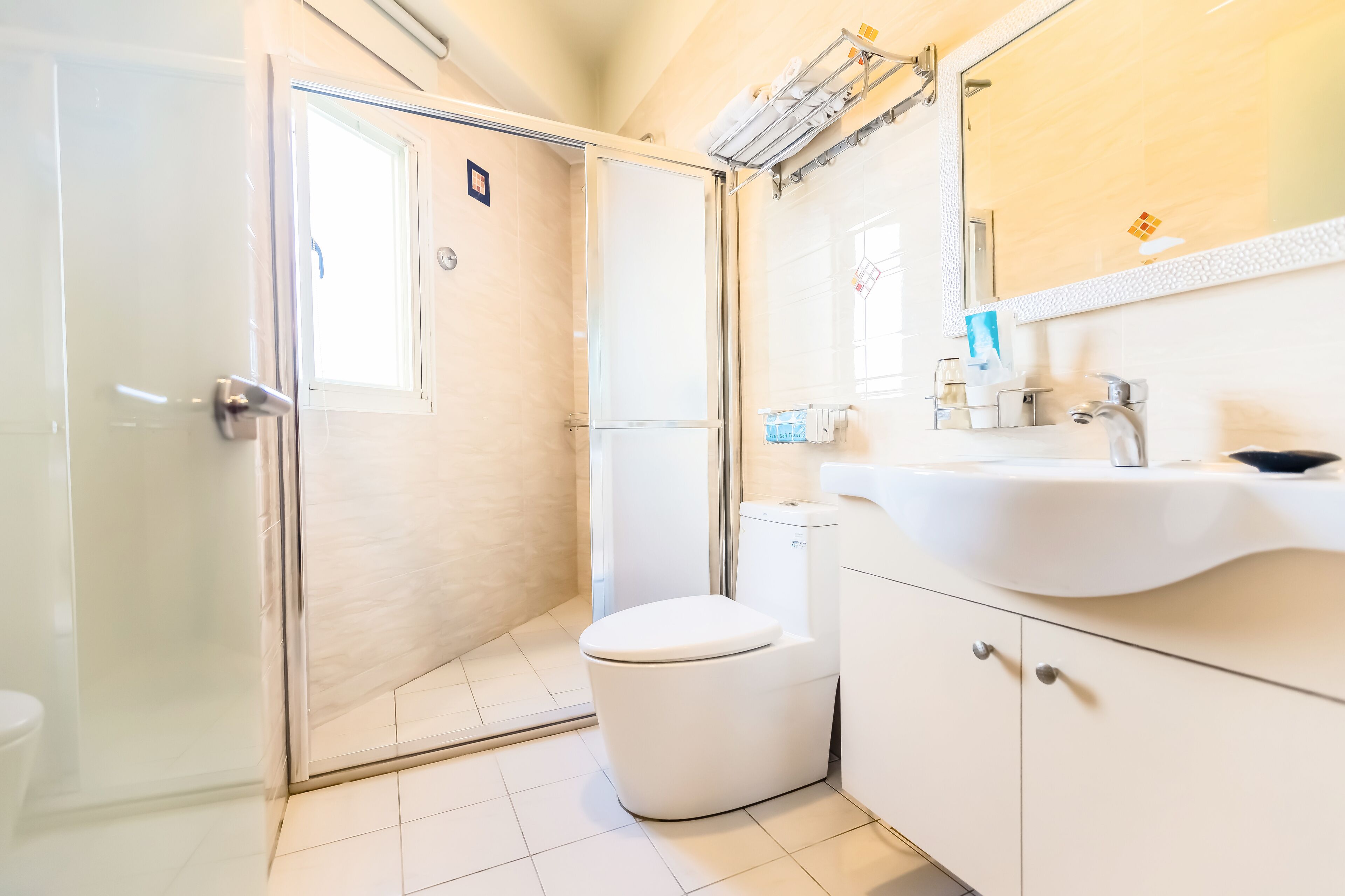 A modern bathroom with a glass shower enclosure, a white toilet, and a sink with a mirror above.