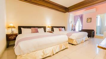 A hotel room with two beds, wooden ceiling beams, a nightstand with a lamp, and a view of the outside.