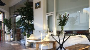A modern outdoor seating area with a glass table, wooden benches, and potted plants. - Tang Villa (Taitung)