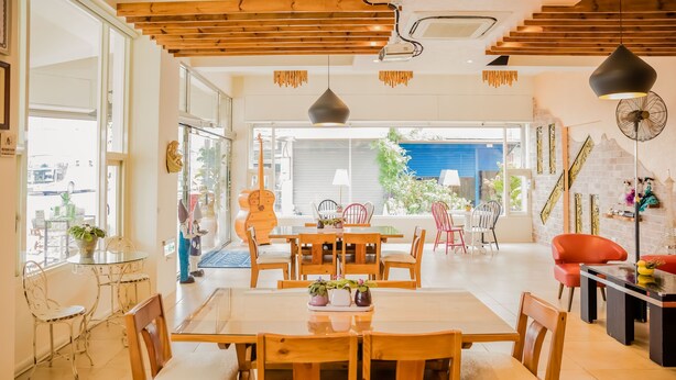 A spacious dining area with a large wooden table and chairs, a glass-top table with chairs, and a view of the outside through large windows. - Tang Villa (Taitung)