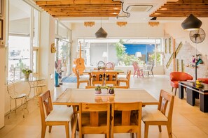 A spacious dining area with a large wooden table and chairs, a glass-top table with chairs, and a view of the outside through large windows. - Tang Villa (Taitung)