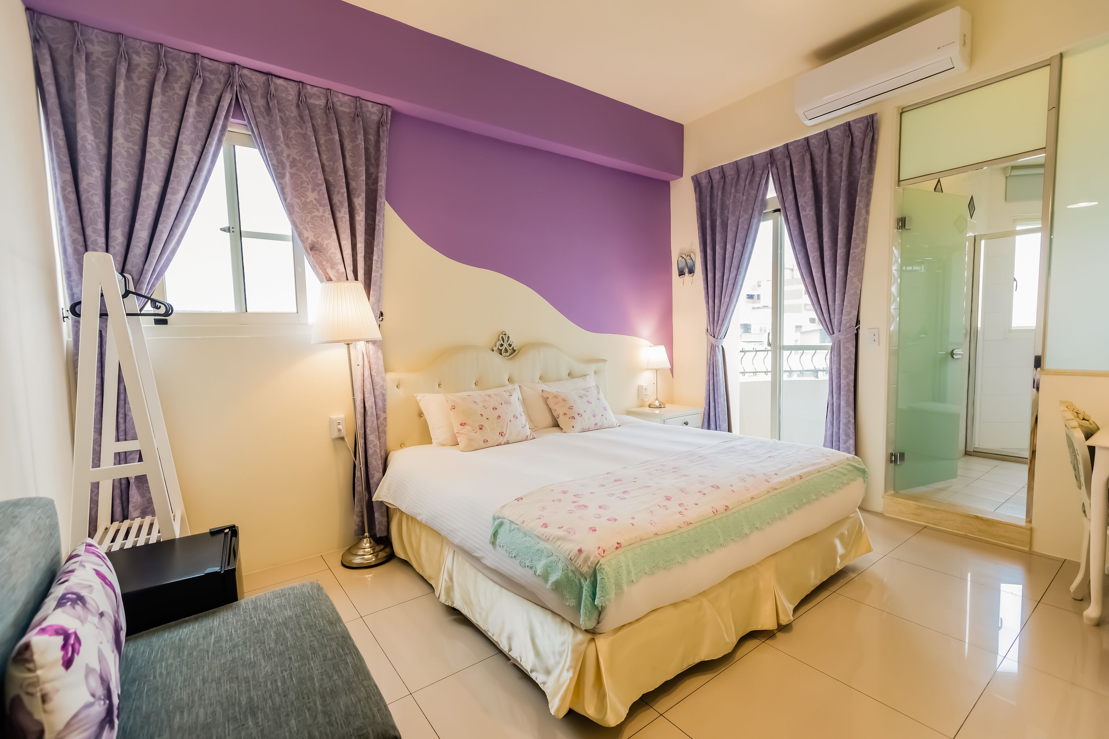 Un dormitorio con cama, mesita de noche, lámpara, armario y puerta corredera al baño.