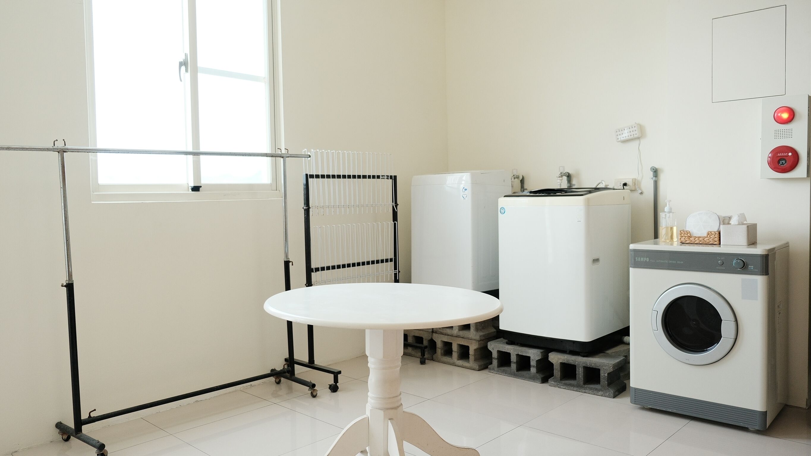 A laundry room with a washing machine, dryer, and a table with a drying rack.