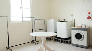 A laundry room with a washing machine, dryer, and a table with a drying rack.
