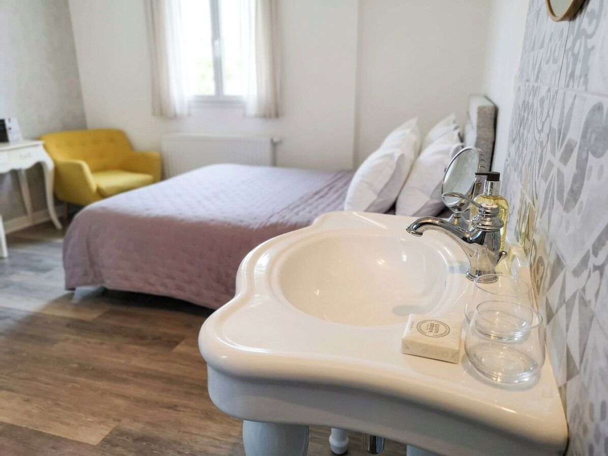 Ein Badezimmer mit einem weißen Waschbecken, einem Spiegel und einem Fenster.