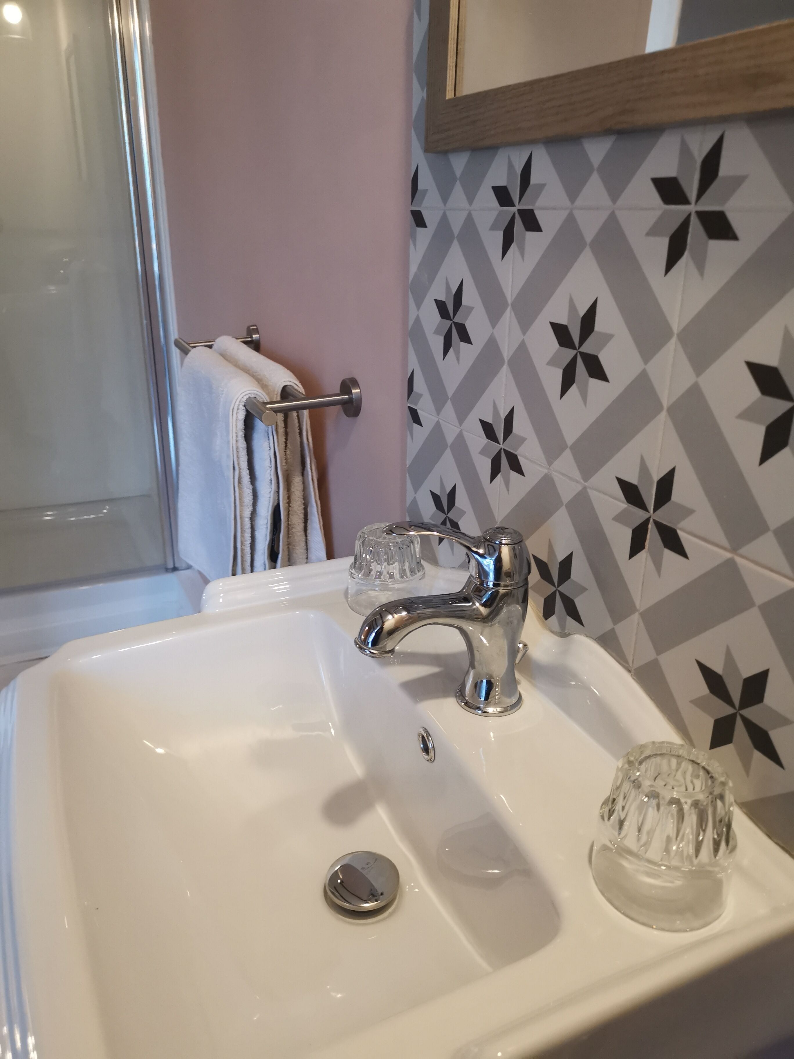 Un lavabo de salle de bain avec un robinet chromé, un porte-savon en verre et un porte-serviettes avec une serviette blanche.