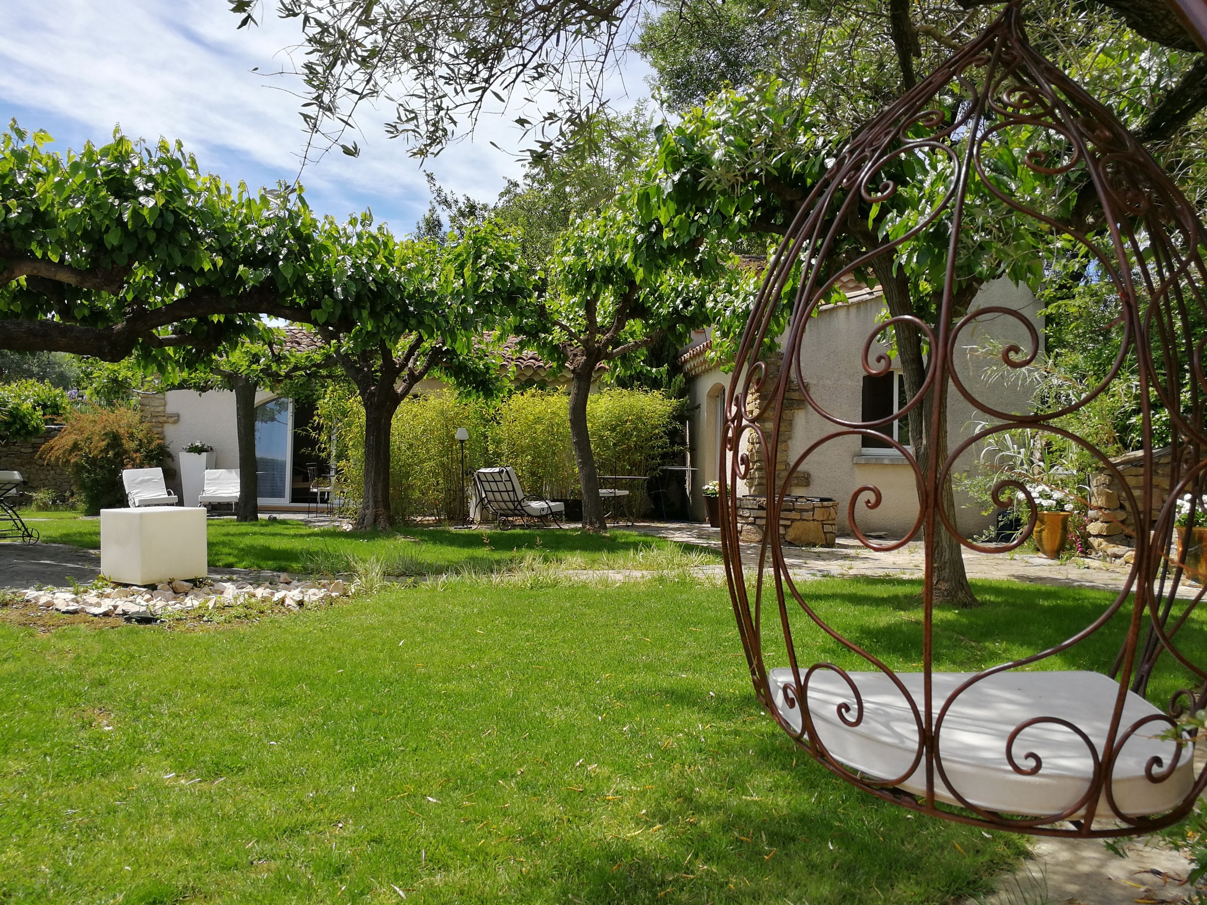 Un jardín con una silla mecedora, un banco blanco y un muro de piedra.