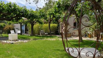 Un jardín con una silla mecedora, un banco blanco y un muro de piedra.