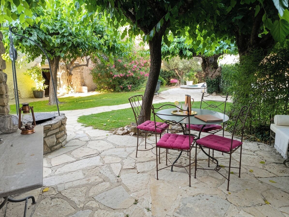 Eine Terrasse im Freien mit Steinboden, einem runden Tisch und vier Stühlen mit Kissen.