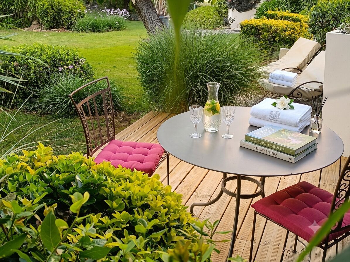 A round table with a vase, three wine glasses, and a book titled 'PROVENCE GARDENS AR LEISURE'.