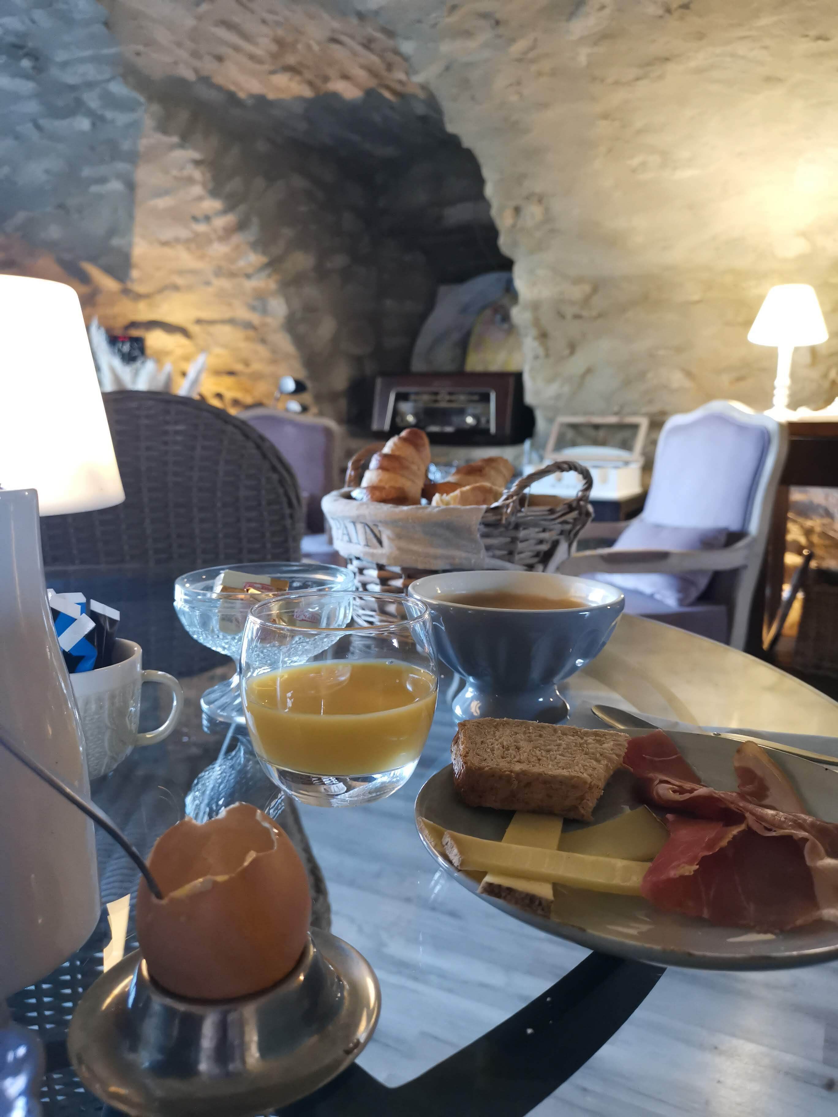 Un plateau de petit-déjeuner avec du pain, des œufs et du jambon, un bol de soupe et un panier de croissants.