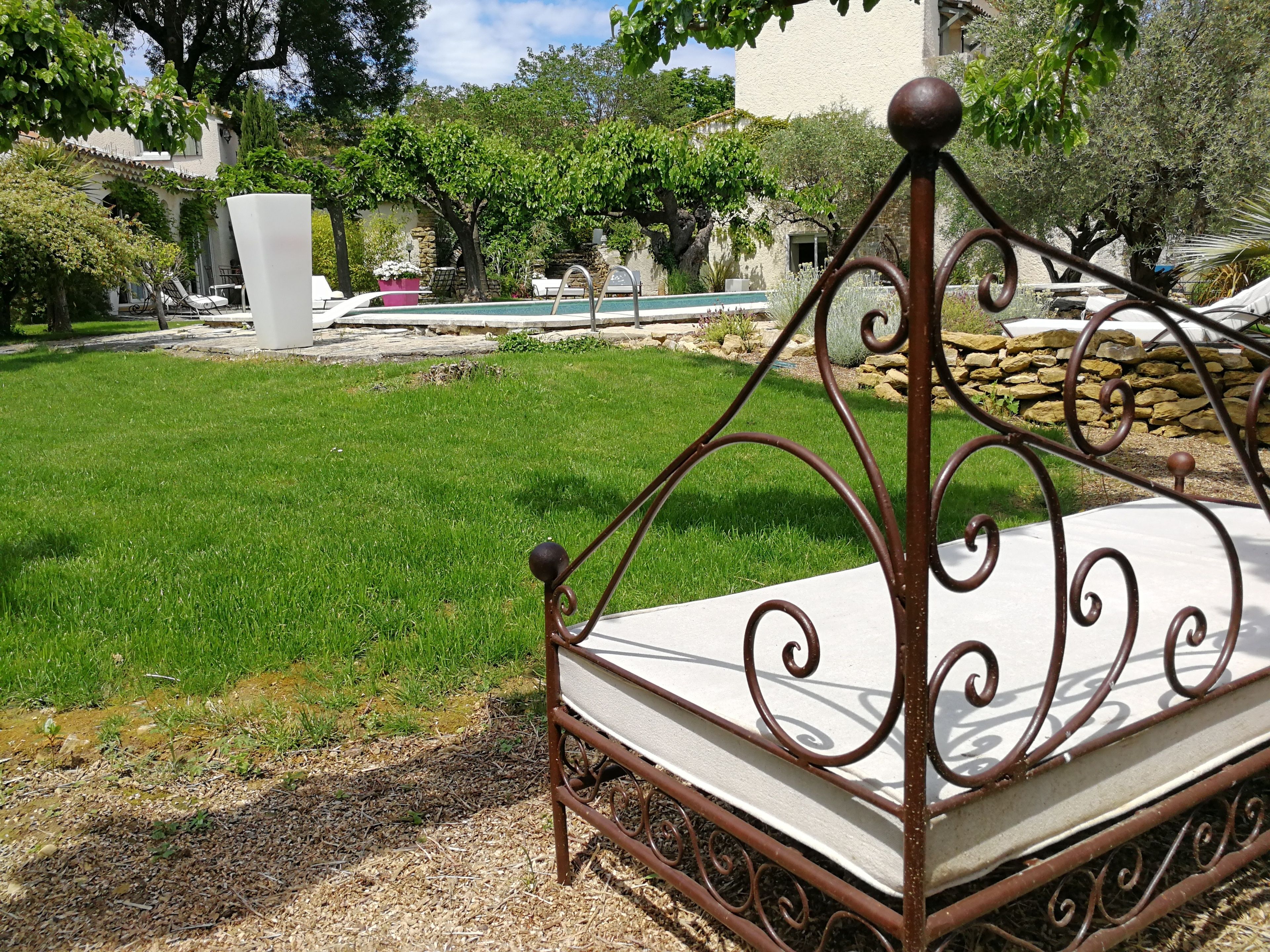 A metal-framed bed with a white mattress in a garden setting.