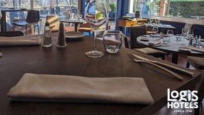 Een restaurantinterieur met gedekte tafels, grote ramen met uitzicht op het buitengebeuren, en een logo voor Logis Hotels.
