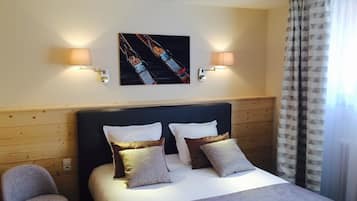 Une chambre d’hôtel avec un lit, deux lampes de chevet, une tête de lit, une chaise et un tableau au mur.