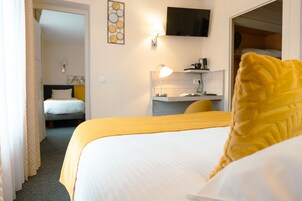 A hotel room with a bed, a desk, a chair, a TV, and a wardrobe.