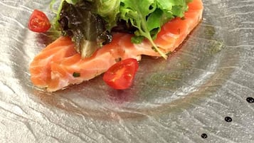 Ein Glasplatten-Teller mit Lachs, garniert mit Salat, Dill und Kirschtomaten.