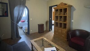 Una sala de estar con un sofá, una mesa de centro de madera, una estantería y un sillón rojo.
