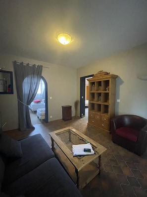 Una sala de estar con un sofá, una mesa de centro de madera, una estantería y un sillón rojo.