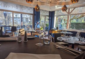 Interior de un restaurante con mesas dispuestas para comer, amplias ventanas que ofrecen vistas al exterior y el logotipo de Logis Hotels.