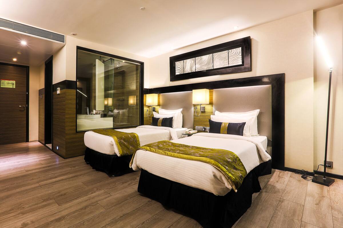 A hotel room with two beds, a large mirror, and a modern design.