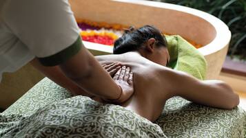 En person modtager massage i et rum med et blomsterfyldt badekar.