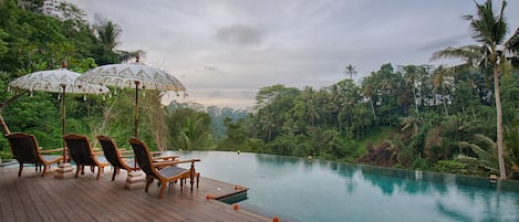 Una piscina al aire libre, sombrillas, sillones reclinables de piscina