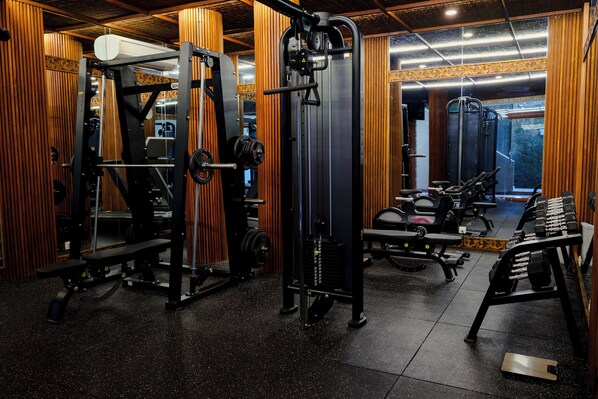 A gym with various exercise equipment, including weight machines and free weights. - Natya Resort Ubud (Ubud)