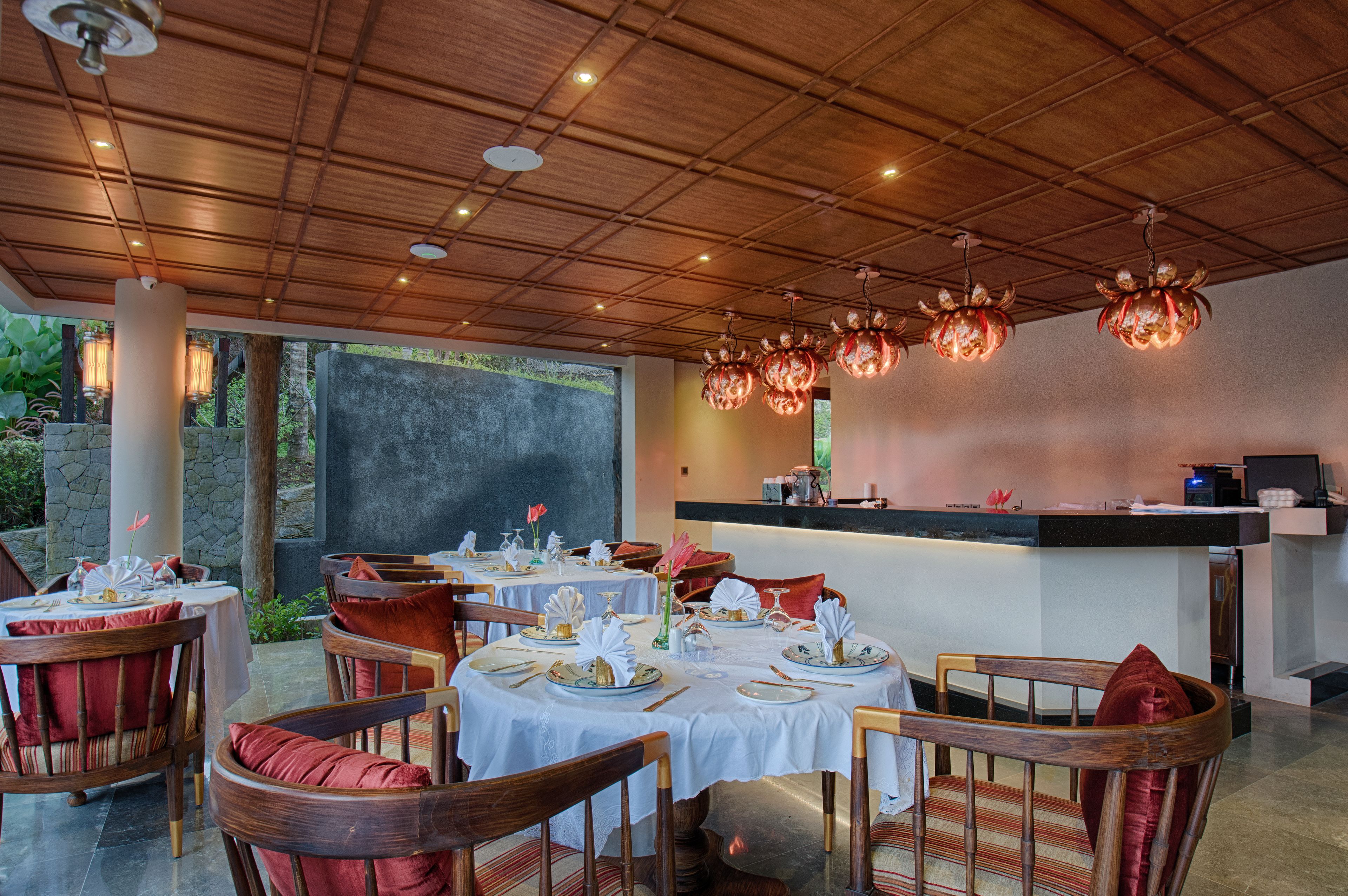 Un restaurante con mesas redondas, sillas de madera y una barra.