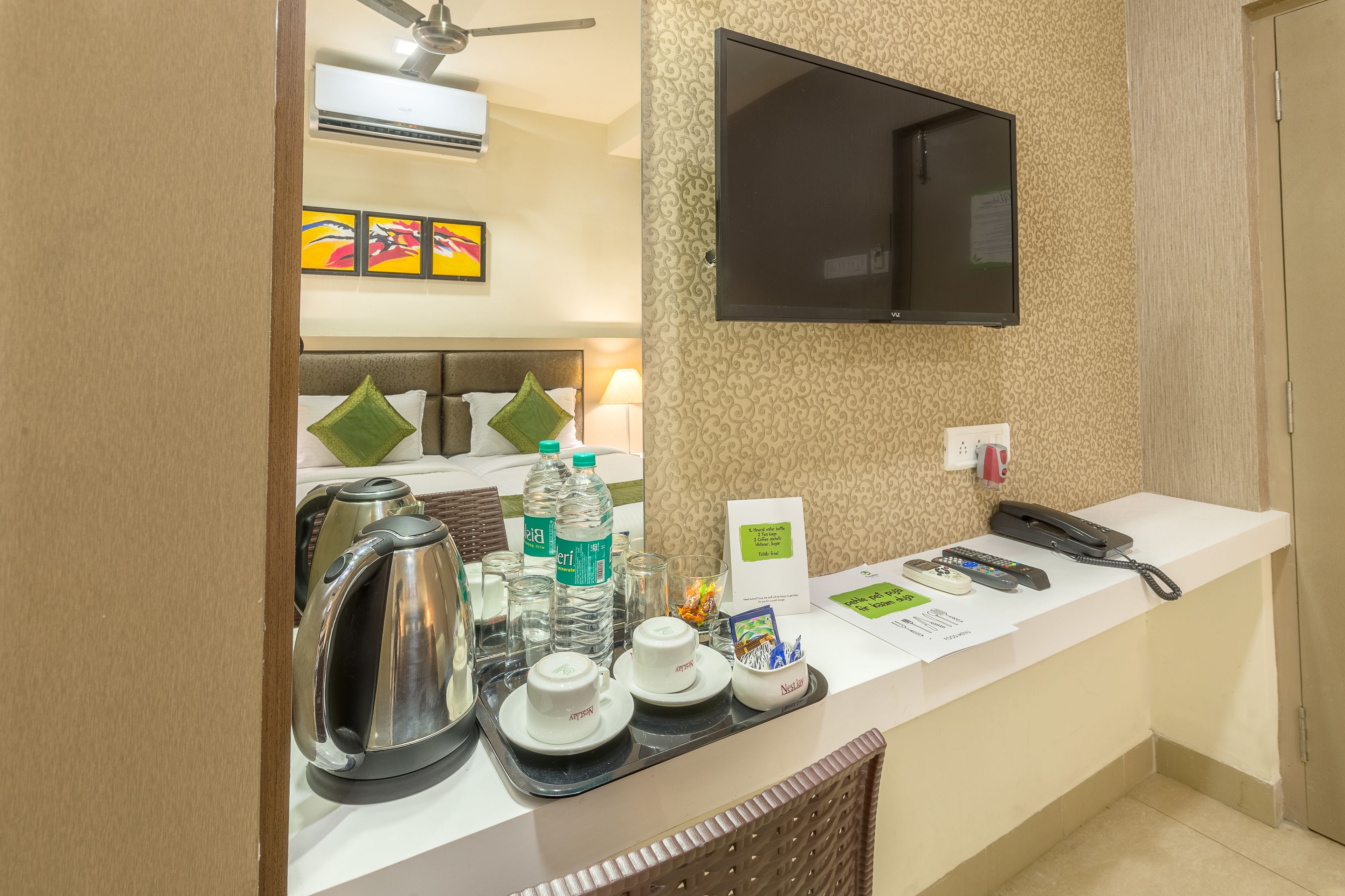 A hotel reception area with a flat-screen TV mounted on the wall, a ceiling fan, and a decorative wall panel.