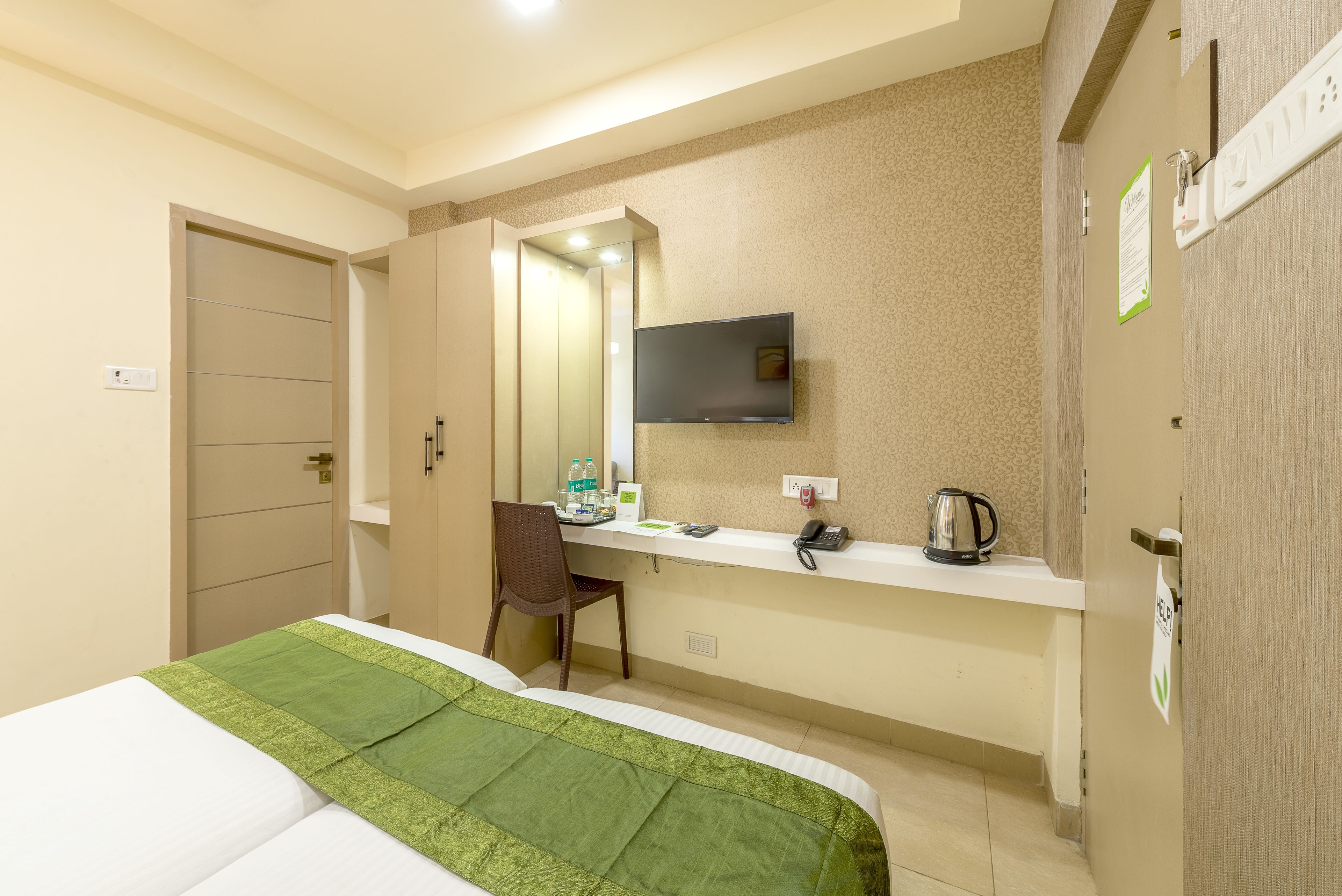A hotel room with a bed, a desk, a chair, a television, and a minibar.
