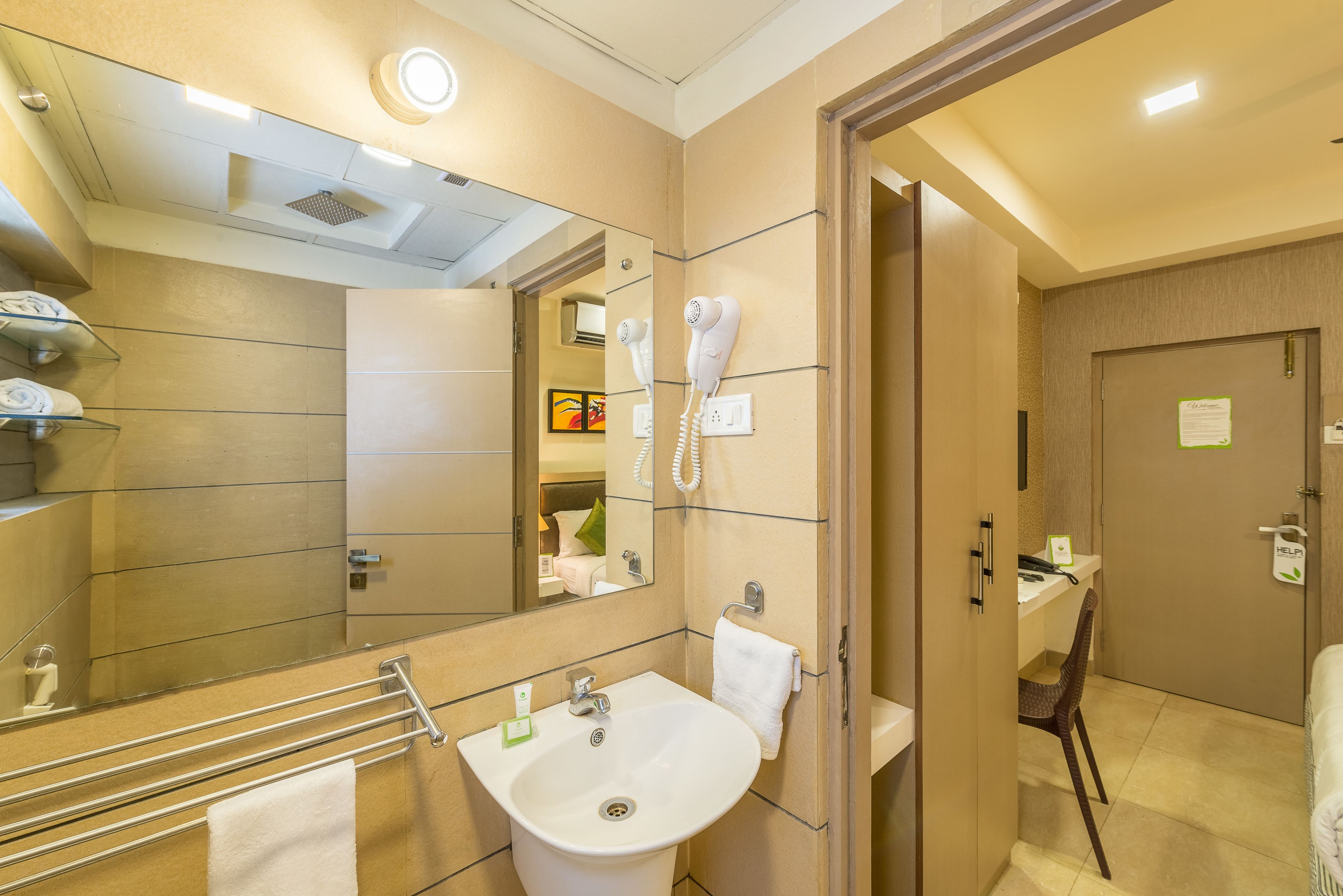 A hotel bathroom with a sink, towel rack, hairdryer, and a mirror.