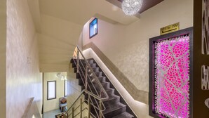 A staircase with a handrail, a door with a number sign, and a decorative wall panel. - Treebo Nestlay Airport Alandur (Chennai)